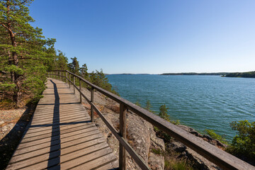 Obraz premium Elevated wooden seaside walkway on a cliff by the Baltic sea in Mariehamn, Åland Islands, Finland, on a sunny day in the summer.