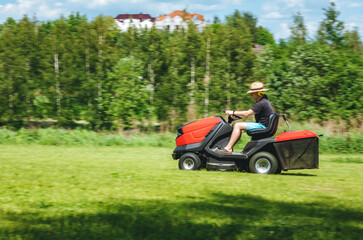 Obraz premium Man on lawn tractor mowing lawn on backyard. The red rider. The lawnmower tractor. High quality 4k footage