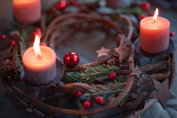 First Advent, wreath with a burning pink candle and Christmas decoration, festive home decoration, copy space, selected focus, shallow depth of field