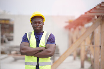 Senior White engineer cross arm at chest looking at camera with smile at work site. Portrait of engineer wearing yeillow hard hat at factory