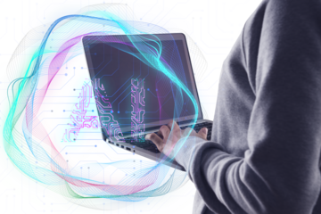 A person using a laptop with colorful abstract digital waves overlayed symbolizing technology and data on a white background