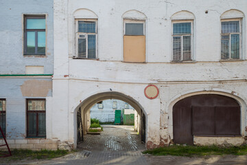 the facade of an old leaning white brick building with arches