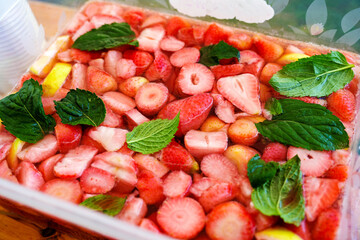 Strawberry bowle or punch with lots of fruits and mint leaves in a square bowl, cold alcoholic party drink from Germany based on fruits, white wine and champagne, selected focus