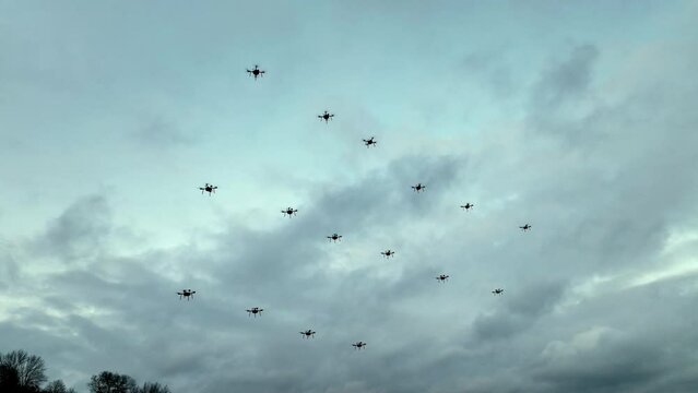 Formation of drones against a cloudy sky. Multiple drones fly in a synchronized formation against a backdrop of a cloudy sky.
