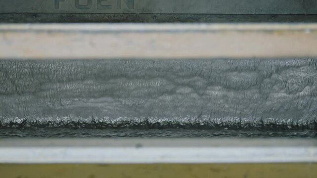 A sheet of galvanized metal moves along a conveyor.