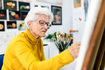 Elderly woman joyfully painting in a bright art studio