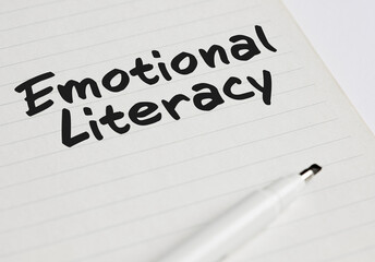 The word emotional literacy written on a notebook with pen marker.