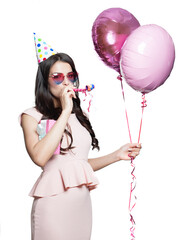 Fashionable brunette woman holding helium balloon isolated on white. Happy model with wavy hair style and trendy make-up excited with pink colour boloons indoor, studio portrait