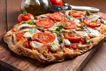 Deliziosa pinsa romana condita con mozzarella, pomodoro fresco e acciughe, cibo italiano 