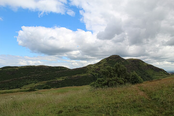 View of Arthur&rsquo;s Seat from Salisbury Crags on blue sky and cloud background in Edinburgh Scotland 