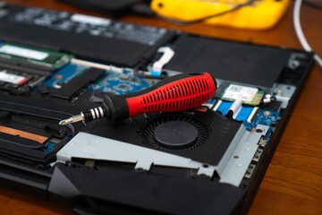 Close-up of a laptop with a red screw and a red plastic tool. Disassemble the computer. Repairing laptop