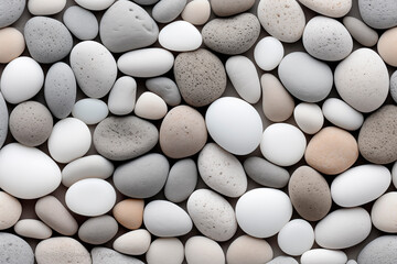 A close-up view of an arrangement of smooth pebbles in varying shades of gray, white, and beige, creating a uniform and tranquil natural pattern.