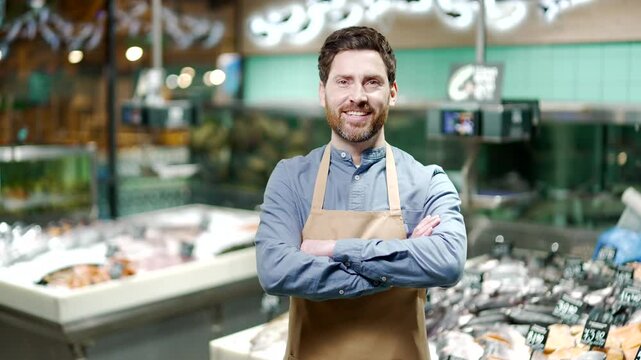 Portrait handsome man worker at seafood market or supermarket fishmonger Manager male small business owner smiling and looking at camera while standing in the store fish department in apron