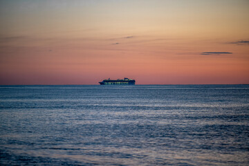 sunrise over the sea with a ship on the horizon
