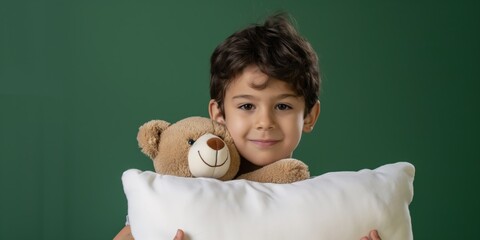 A cute boy hugging a teddy bear and a pillow, capturing a moment of childhood tenderness.