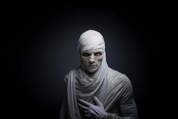 A young man dressed as a Mummy for Halloween standing in front of a white isolated background