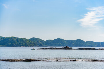 A fisherman in a fishing boat in Nachi bay, Japan. Scenic cview from the Pacifi coast in Nachikatsuura, Higashimuro District, Wakayama