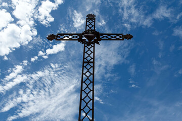 Obraz premium Iron cross depicting the sacred heart of Jesus on a sunny blue sky background. Croix de fer représentant le cœur sacré de Jésus sur fond de ciel bleu ensoleillé.