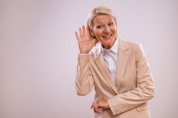 Portrait of  happy  mature businesswoman listening on a gray background.