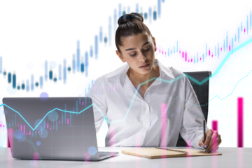 A professional woman analyzing data on her laptop with superimposed financial graphs, white shirt, bright office environment