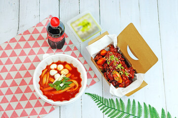 식탁 위에 닭강정과 떡볶이 음료수가 놓여 있는 모습