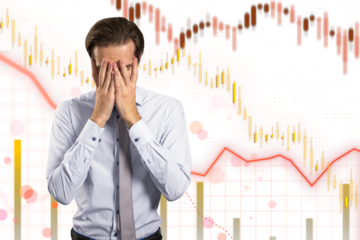 A stressed businessman with hands on his face against a financial chart background, depicting concept of market crash or loss