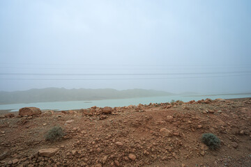 Panoramic view of Al Wahda Dam, with towering power lines and sparse vegetation. Al Wahda Dam, River Ourgaha, Morocco.