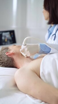 Doctor woman with white medical gloves performing neck ultrasound exam on male patient