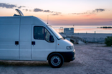 Camper van parked on a beach at sunset in Sardinia, Italy