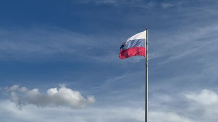 the flag of the Russian Federation flutters in the wind against the background of a blue cloudy sky from bottom to top