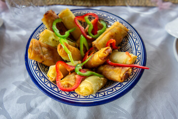 A plate of golden-brown fried delicacies, filled with chicken and vegetables, garnished with fresh bell peppers. A culinary delight on the journey to Chefchaouen, Morocco.