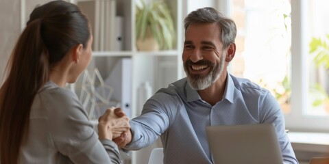 Obraz premium Smiling Middle-Aged Businessman and HR Manager Shaking Hands with New Employee during Office Meeting, Celebrating Labor Day and Workplace Dedication in a High-Resolution AI-Generated Wallpaper