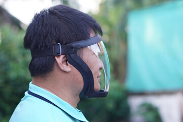 Asian man wears protective safety face shield. Concept, tool, equipment use for wearing with face to protect from dust, germ spreading or others into face. Work Secured helmet shield.          