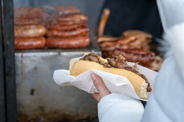 Puesto de choripanes argentinos entregando un sandwich de bondiola