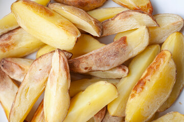 Close up of fresh made fried potato chunks on a piece of baking paper. Healthy food concept