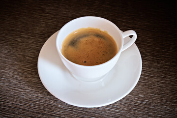 A cup of fragrant morning coffee on the table. White cup with freshly brewed coffee on a dark...