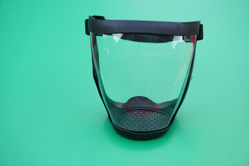 Protective safety face shield, Clear glass with black edge. Green background. Concept, tool, equipment use for wearing with face to protect from dust, germ spreading or others into face. Work Secured.