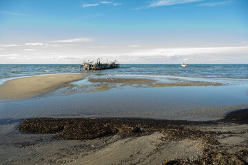 Fishing pontoon or hulk. Beauduc, salin de Giraud, Arles, Provence, France. Evening light, sand, beach, coastline. White clouds blue sky.