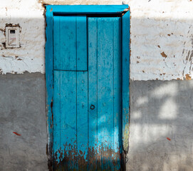 Artistic and creative shot of an old blue door and a weathered adobe wall. Jardin, Jardín, Antioquia, Colombia.