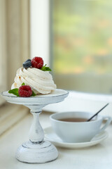Tea in a beautiful white cup, cake with berries and white hydrangea flowers.