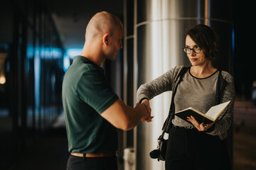 Business professionals shaking hands at night, discussing work and collaborating outdoors while holding a notebook. Casual yet professional nighttime meeting setting.