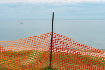 orange plastic snow fence (used here as a simple barrier) with view of the lake and sky