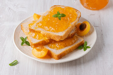Toasts with tasty apricot jam on a white wooden table