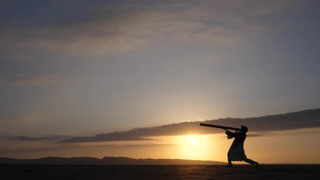 man with didgeridoo at the sunset