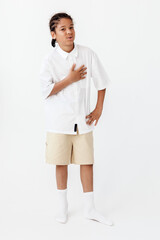 Fototapeta premium Young boy in trendy outfit poses confidently against blank white backdrop