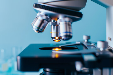 Close-up of modern microscope in laboratory, focusing on lens, blurred background, macro photography, medical science and research.