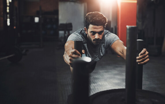Man, sled and push in gym for fitness or muscle endurance, leg strength and speed improvement with exercise. Male person, cardio workout and training in recreation center, agility and athlete.