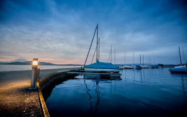 The harbor of Zug with sailing ships on a cold winter evening
