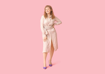Happy young woman in stylish beige dress on pink background
