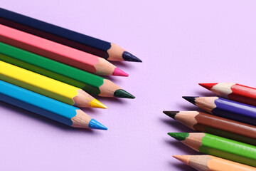 Colorful pencils on purple background, closeup